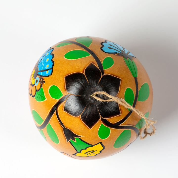 Hand-painted gourd birdhouse close-up with black flower design and green leaf accents