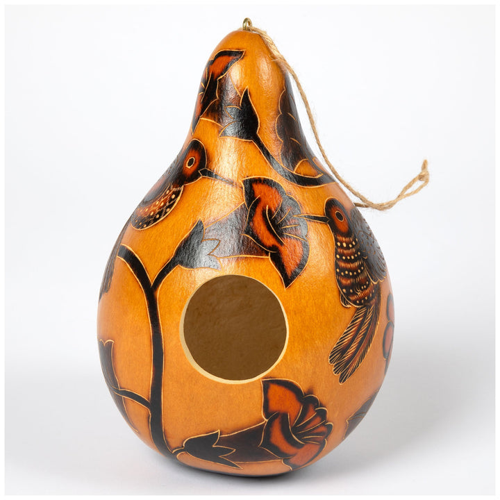 Orange gourd birdhouse with black painted designs, round opening and hanging twine