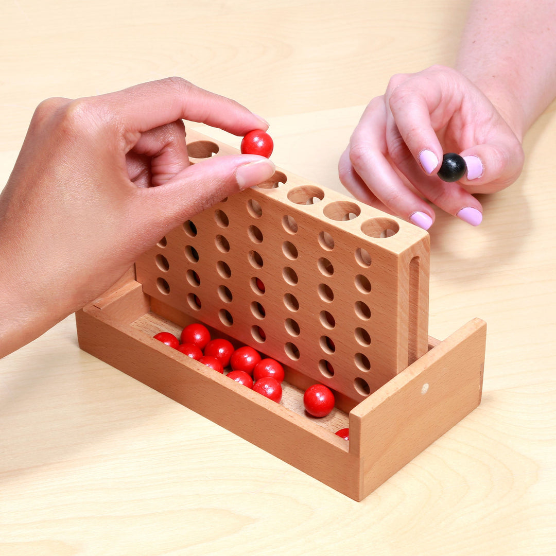 Hands placing red and black pegs into a wooden peg board game