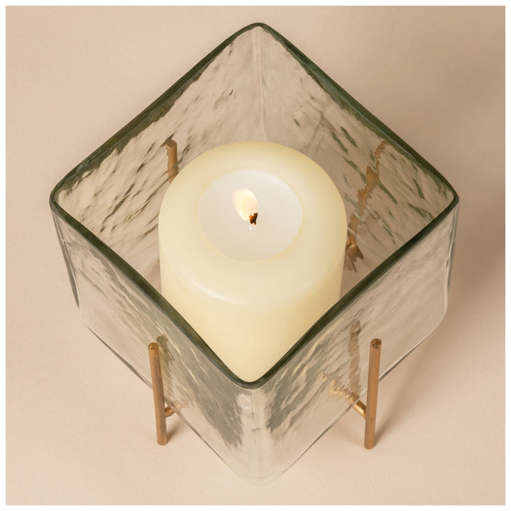 Diamond-top square glass tea light holder with burning candle and brass support legs