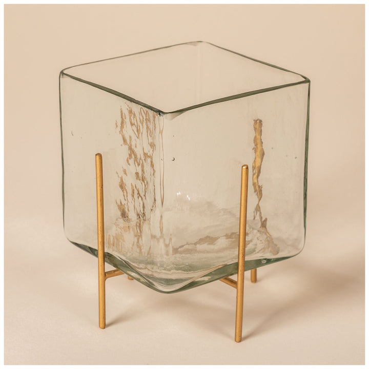 Square glass tea light holder with burning candle, clear panels on brass legs