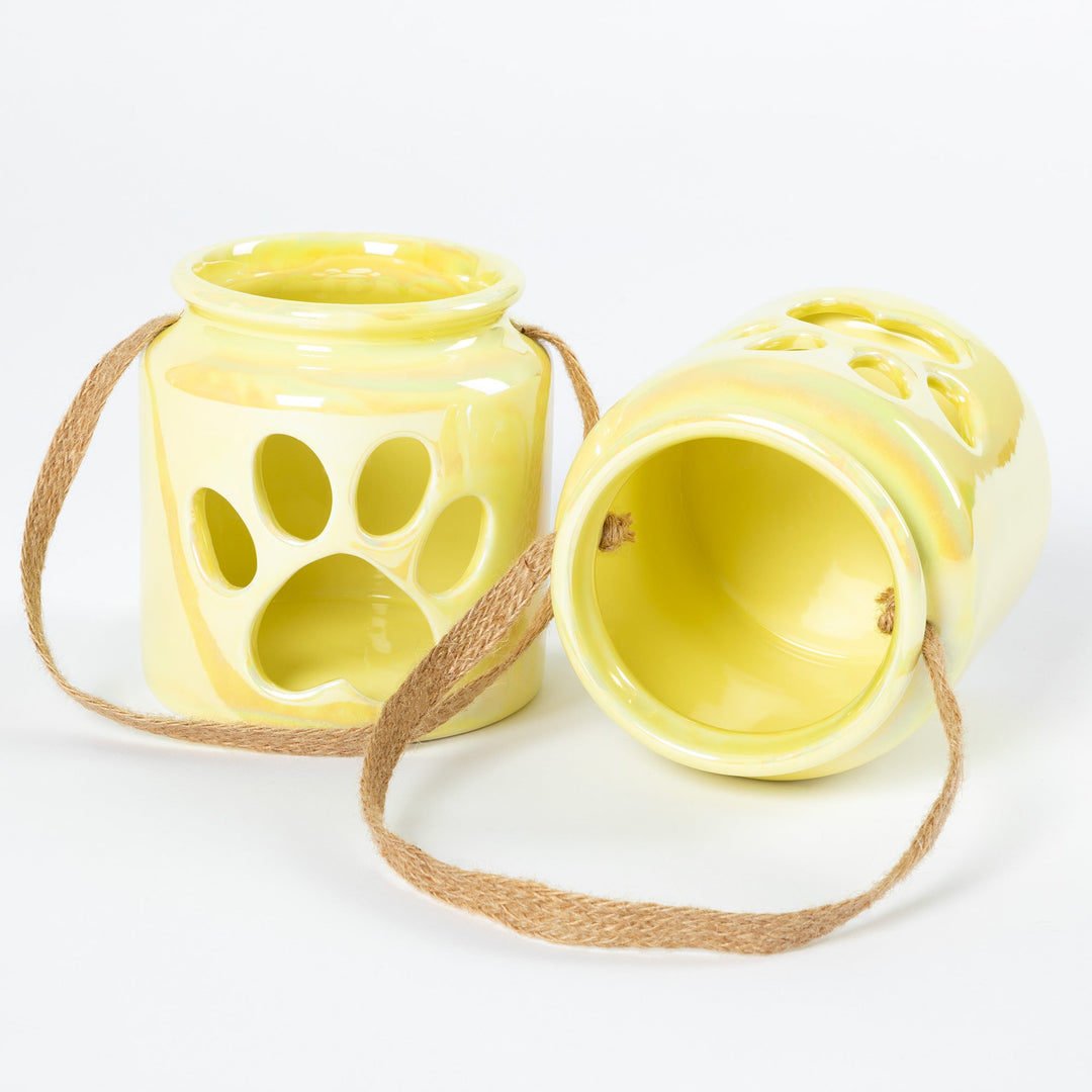 Cream paw-print glass candle holders, one open for candle access, with rope handles