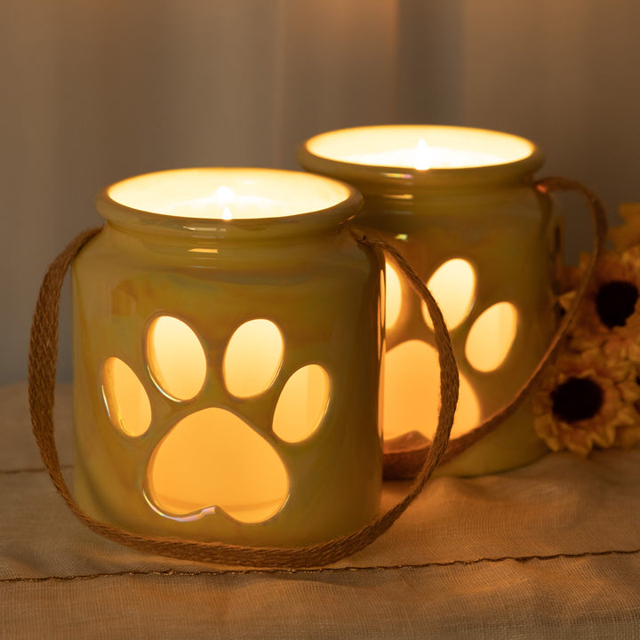Set of 2 yellow paw-print glass candle holders with lit candles and rope handles
