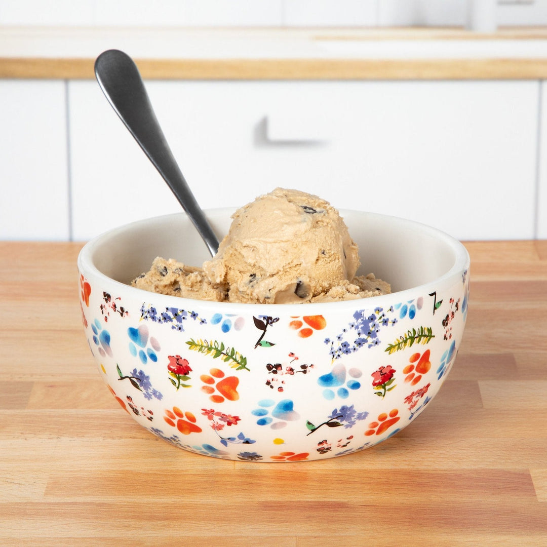 Ceramic soup bowl with colorful paw-and-flower print, with serving spoon