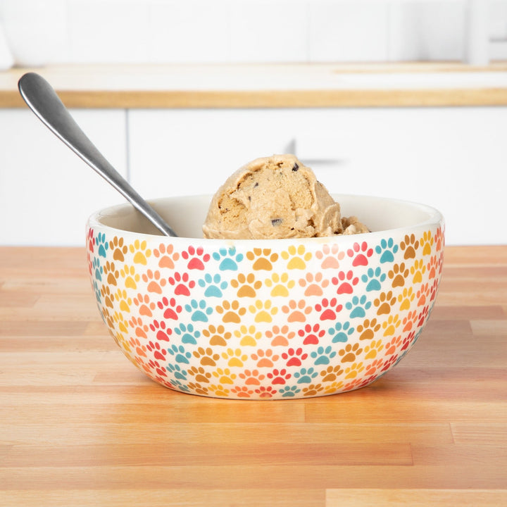 Ceramic soup bowl with multicolor paw-print design, filled with food and spoon