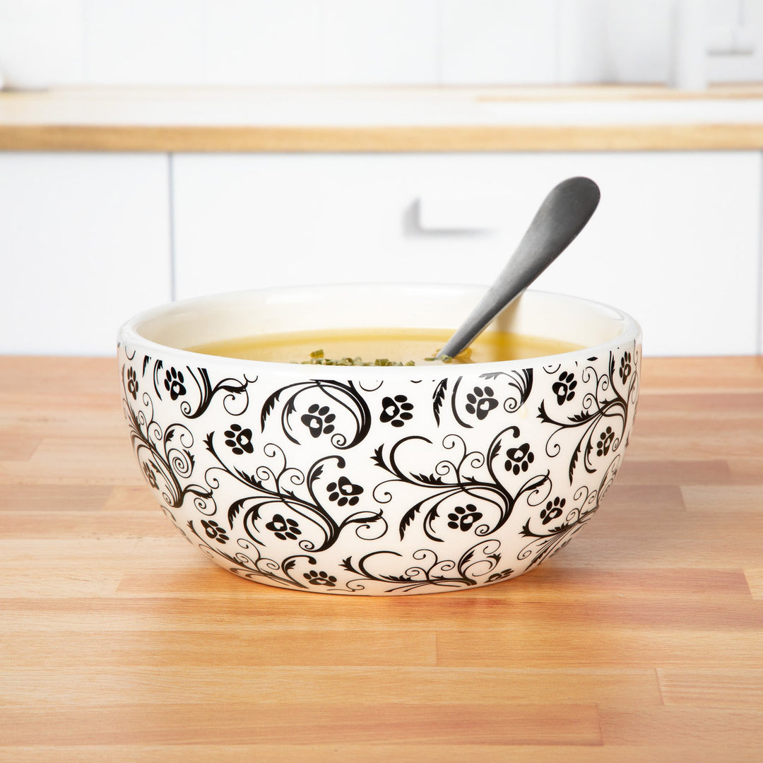 Ceramic soup bowl with black swirls and paw prints, with serving spoon