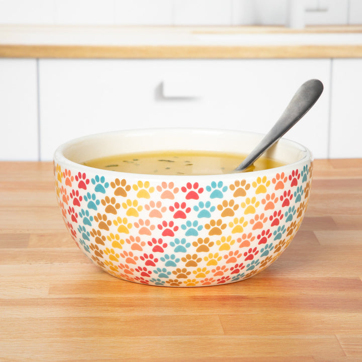 Ceramic soup bowl with multicolor paw-print speckled design and spoon