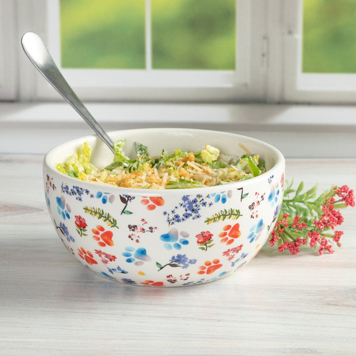 Ceramic soup bowl with colorful paw-and-flower print, filled with salad