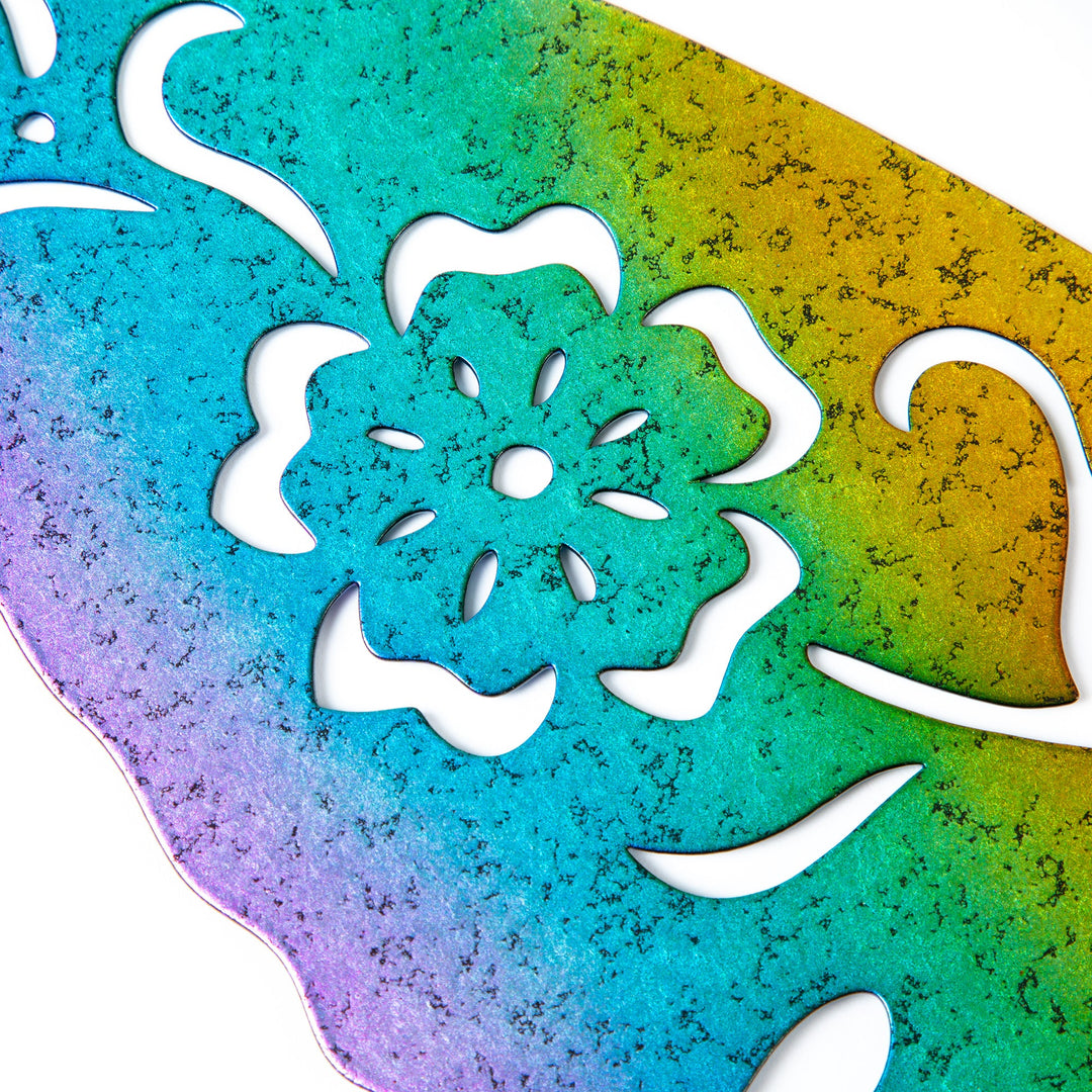 Close-up of iridescent green and gold metal hummingbird silhouette with white leaf cutout