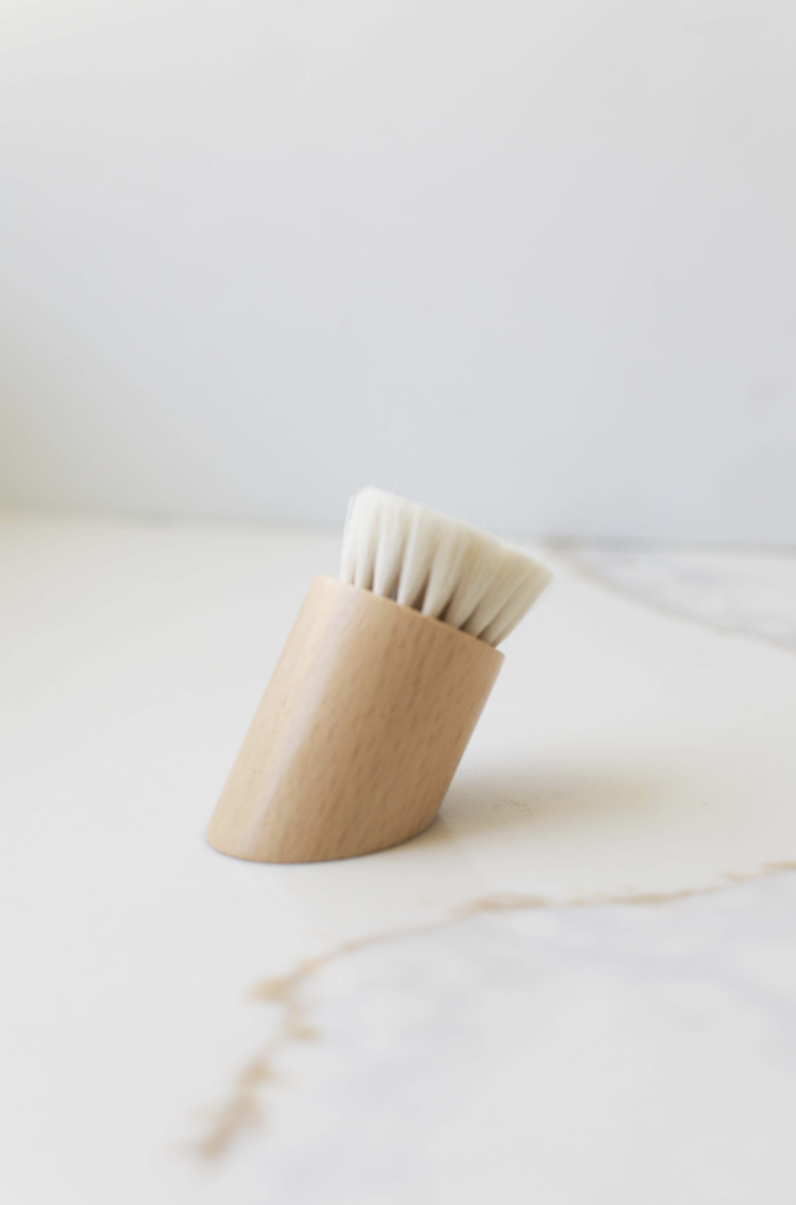 Face brush with wooden handle and white bristle head