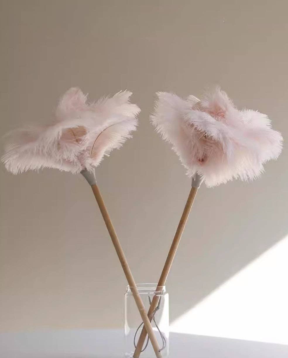 Pair of pink ostrich feather dusters on a double wooden handle with secured ties