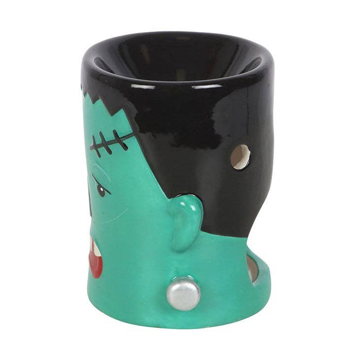 Halloween monster oil burner, teal ceramic body with black face patch and silver side knobs.