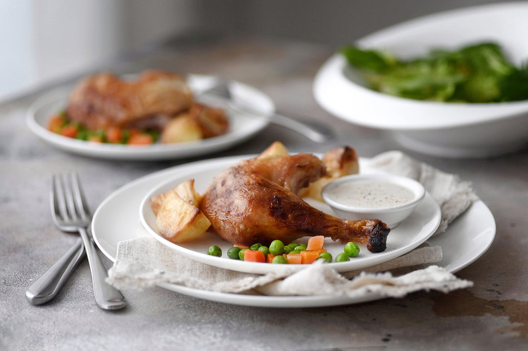 White dinner plate with smooth rim, shown with small side dishes.
