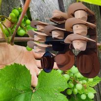 Hand placing a light tan hat onto a wall-hanging organizer hook on wooden rail