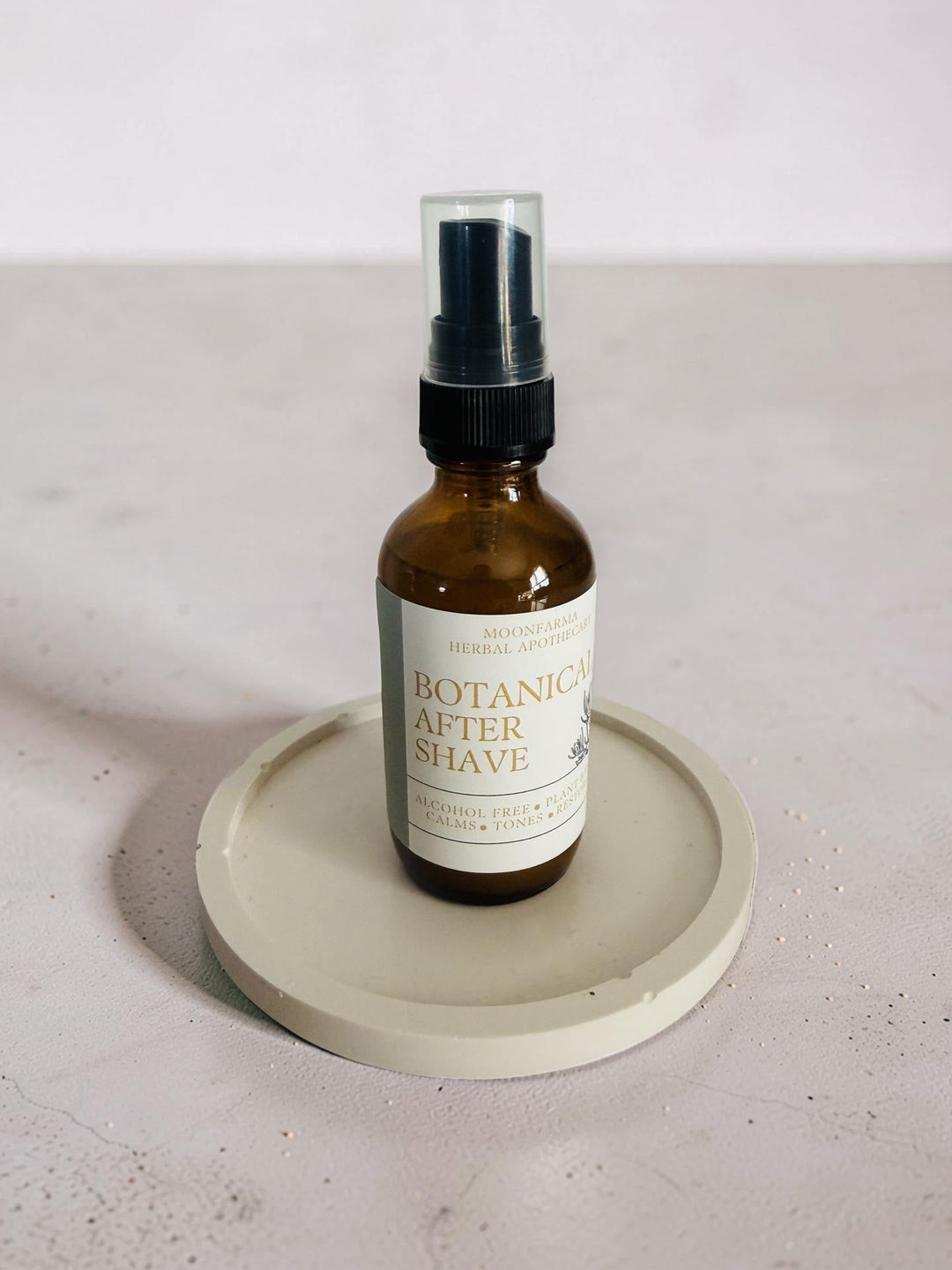 Botanica after shave spray bottle with black pump on a round tray
