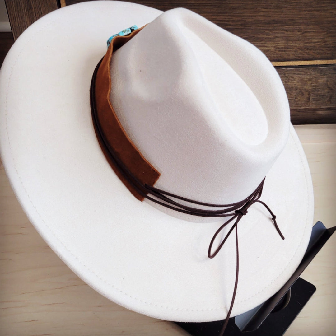 Tan suede hat band detail with turquoise patch and tied leather cords