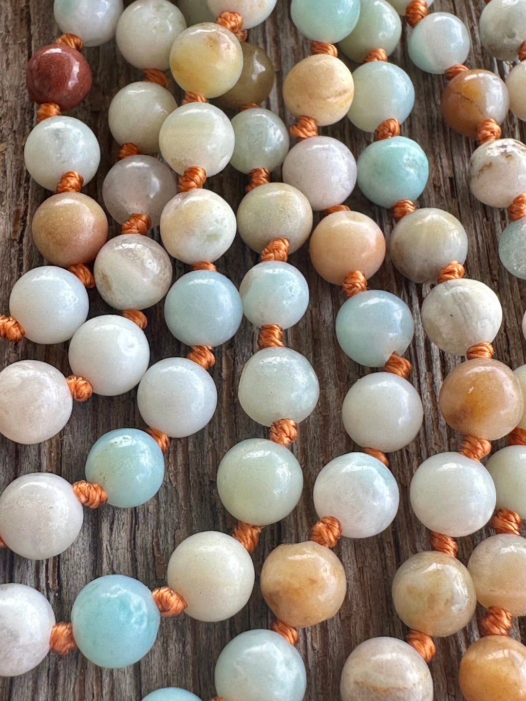 Close-up of round multi-color beads with copper-brown spacers on a necklace strand.