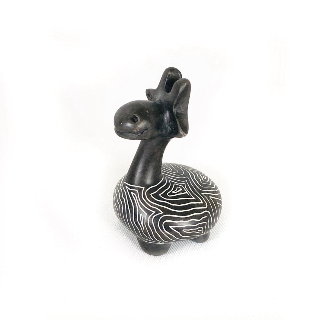 Soapstone giraffe figurine with dark body and white wavy stripe belly, facing left