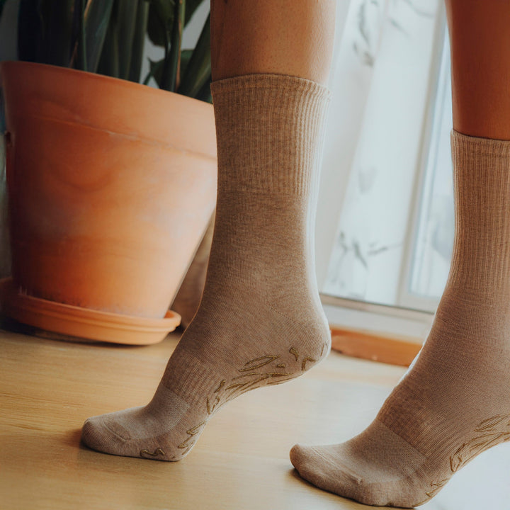 Brown crew socks with grip pattern on soles, shown on standing legs