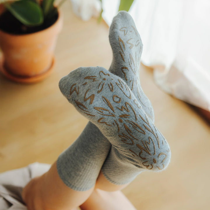 Grey crew socks showing gold floral grip print on sock sole