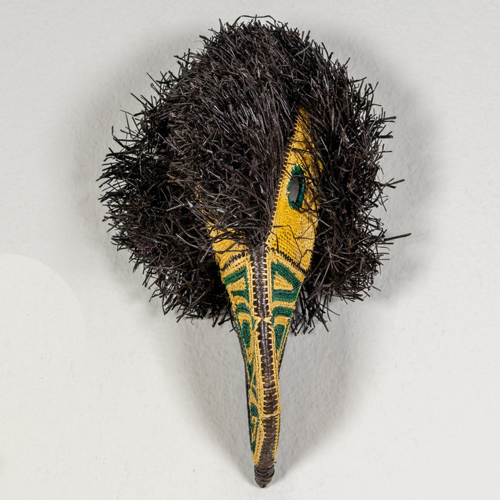 Toucan mask from above with black shag body and yellow beak with green accents