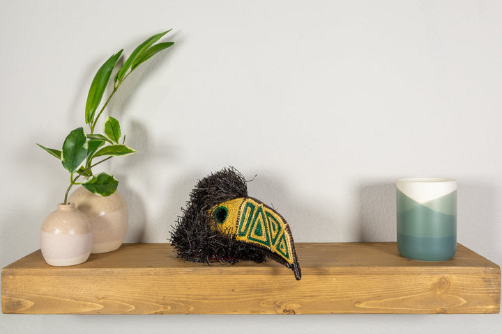 Toucan mask lying down with black shag fur, yellow face, and green geometric trim