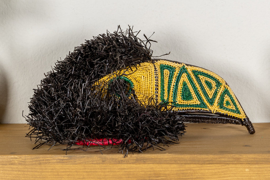 Toucan mask low angle with black shag, yellow face, and teal-green geometric stripes