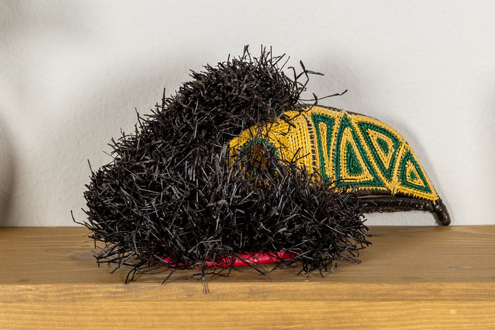 Toucan mask close side profile with black shag and yellow beak with green embroidered patterns