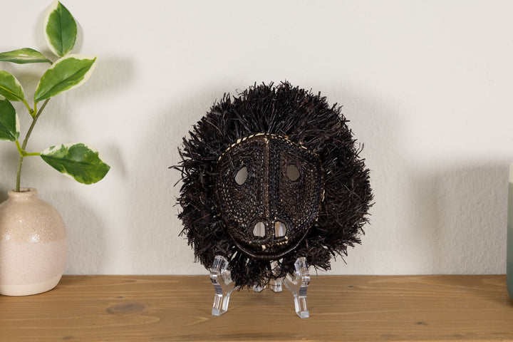 Black howler monkey mask on clear stand with spiky fur and woven face detailing