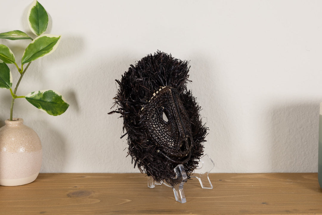 Black howler monkey mask viewed from behind on a clear display stand