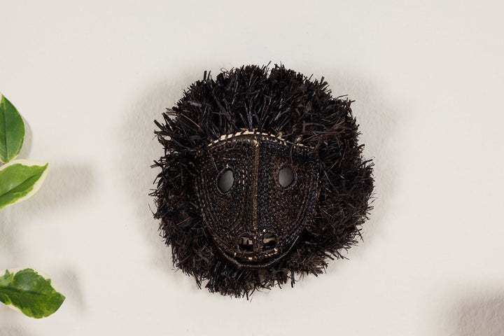 Black howler monkey face mask with round eye cutouts and woven textured surface