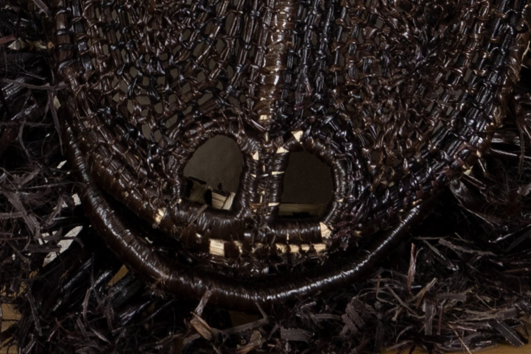 Close-up of black woven muzzle and open mouth on a spiky howler monkey mask