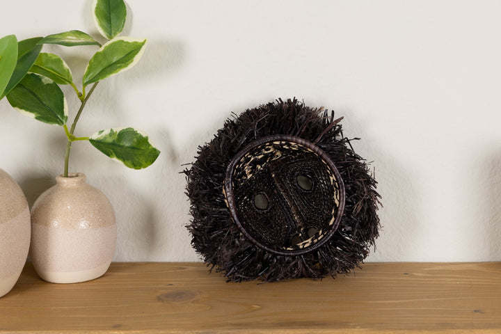 Front view black howler monkey mask with spiky fur and woven face panel on stand