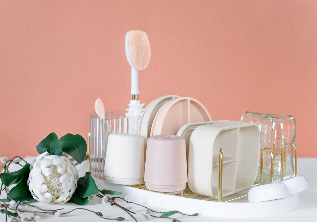 Gold countertop dish drying rack with bottle brush, glassware slots, and white dish items