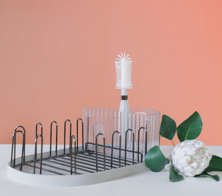 Countertop dish drying rack with black metal bars and white bottle brush