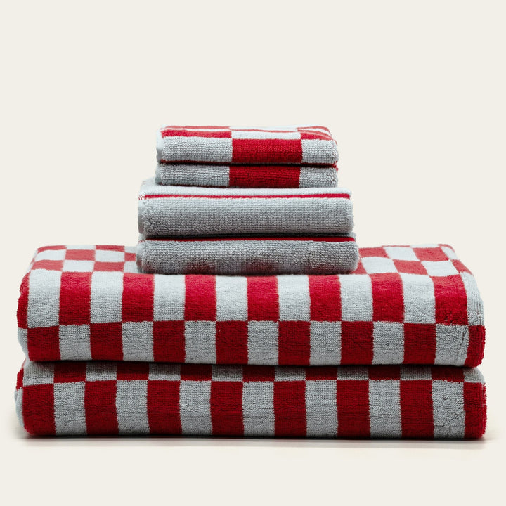 Stack of red and white checkered cotton towels with striped folded edges.