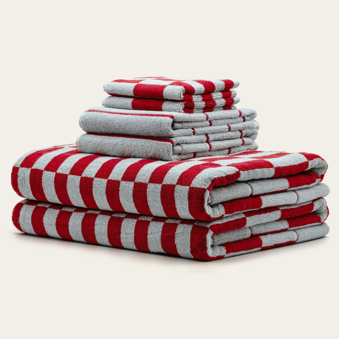 Pile of red and white checkered cotton towels, neatly folded stack.