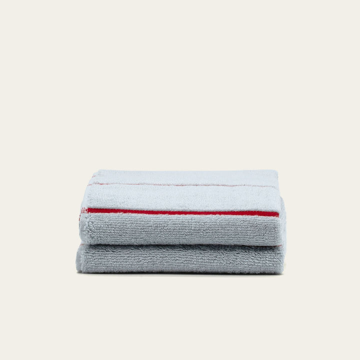 Two folded gray cotton towels with red striped border stacked side by side.