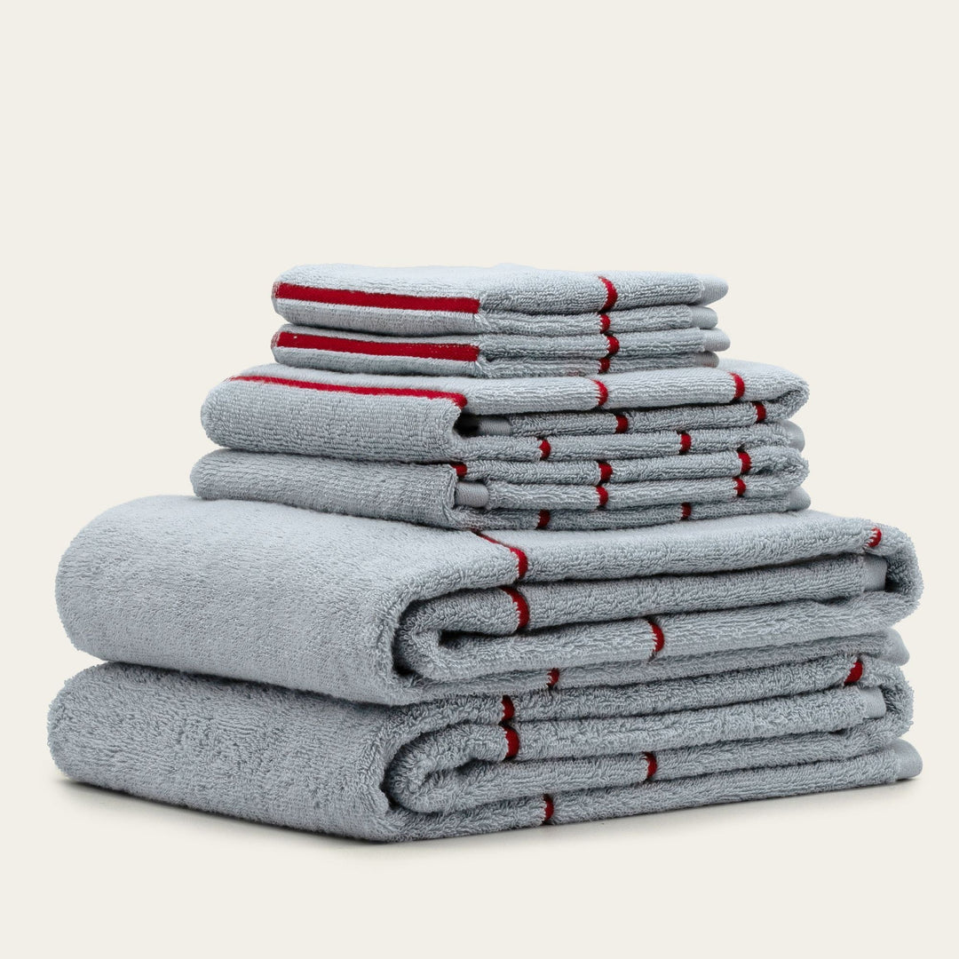 Multiple folded gray cotton towels with red striped accents stacked in a tower.