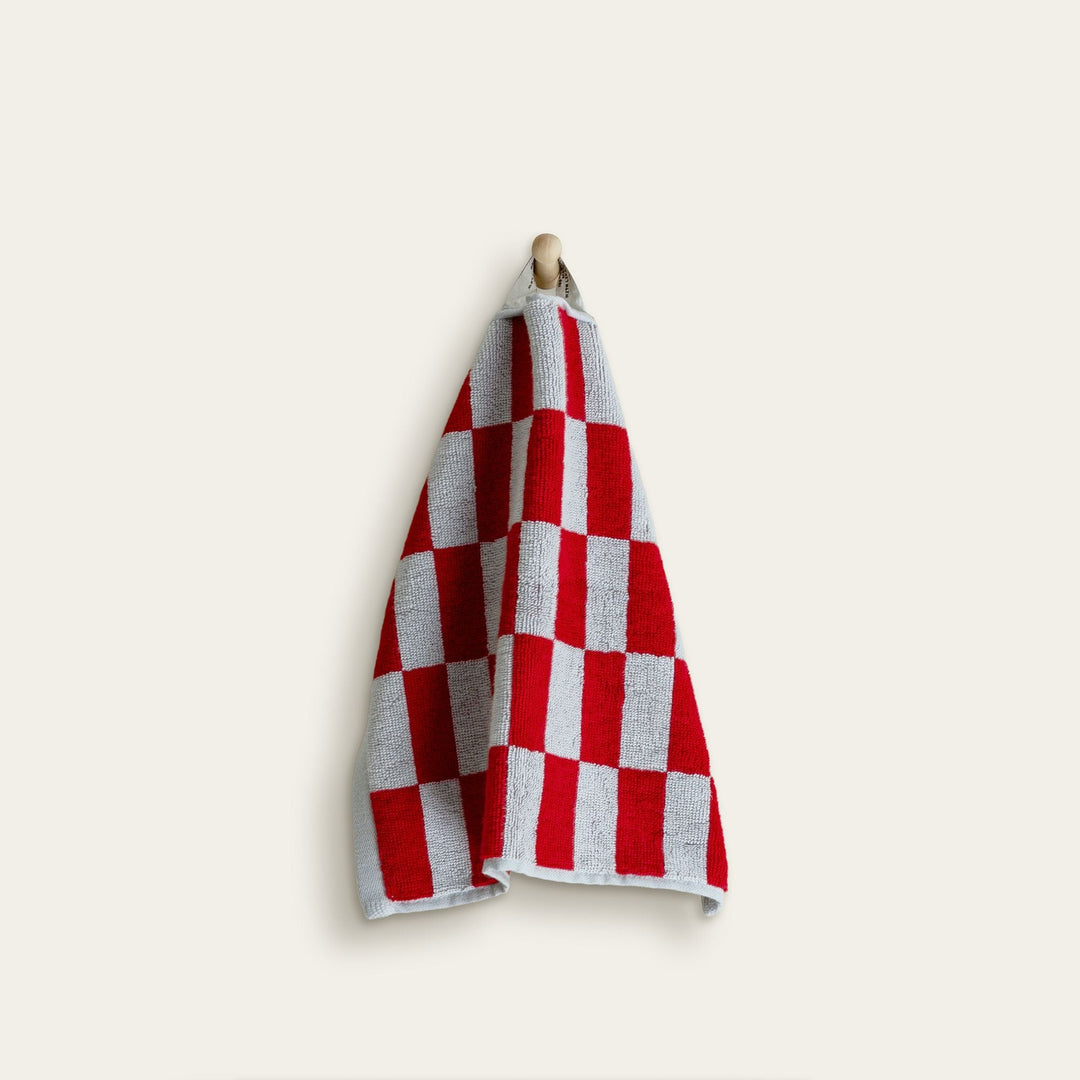 Hanging red and white check cotton towel with folded edge.
