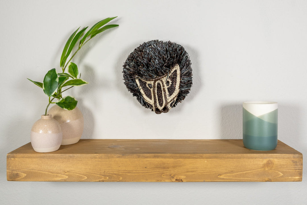 Colobus monkey mask on clear stand with dark fringe and cream embroidered face