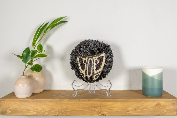 Colobus monkey mask on clear tripod stand with dark fringe and cream face embroidery