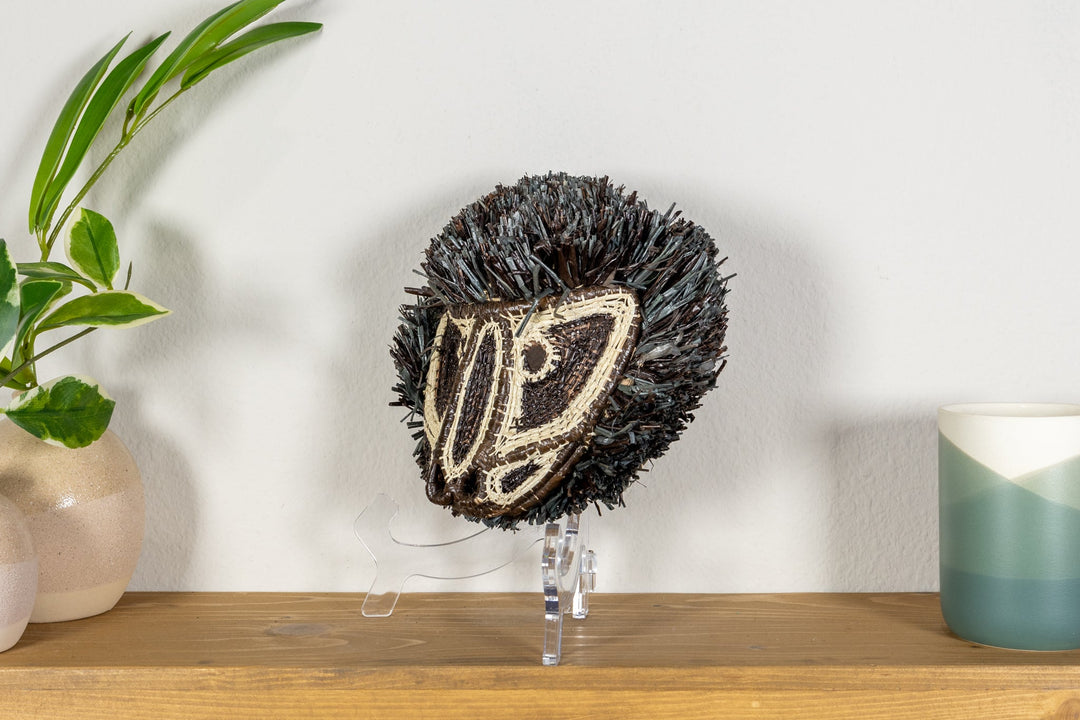 Colobus monkey mask on clear stand with dark fringe and cream embroidered face