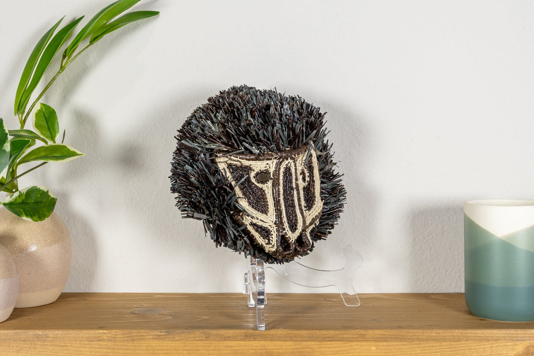 Colobus monkey mask angled view with dark fringe and cream striped face embroidery