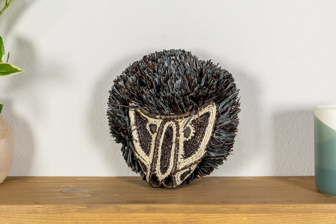 Colobus monkey mask front view with dark shag fringe and cream striped embroidered face