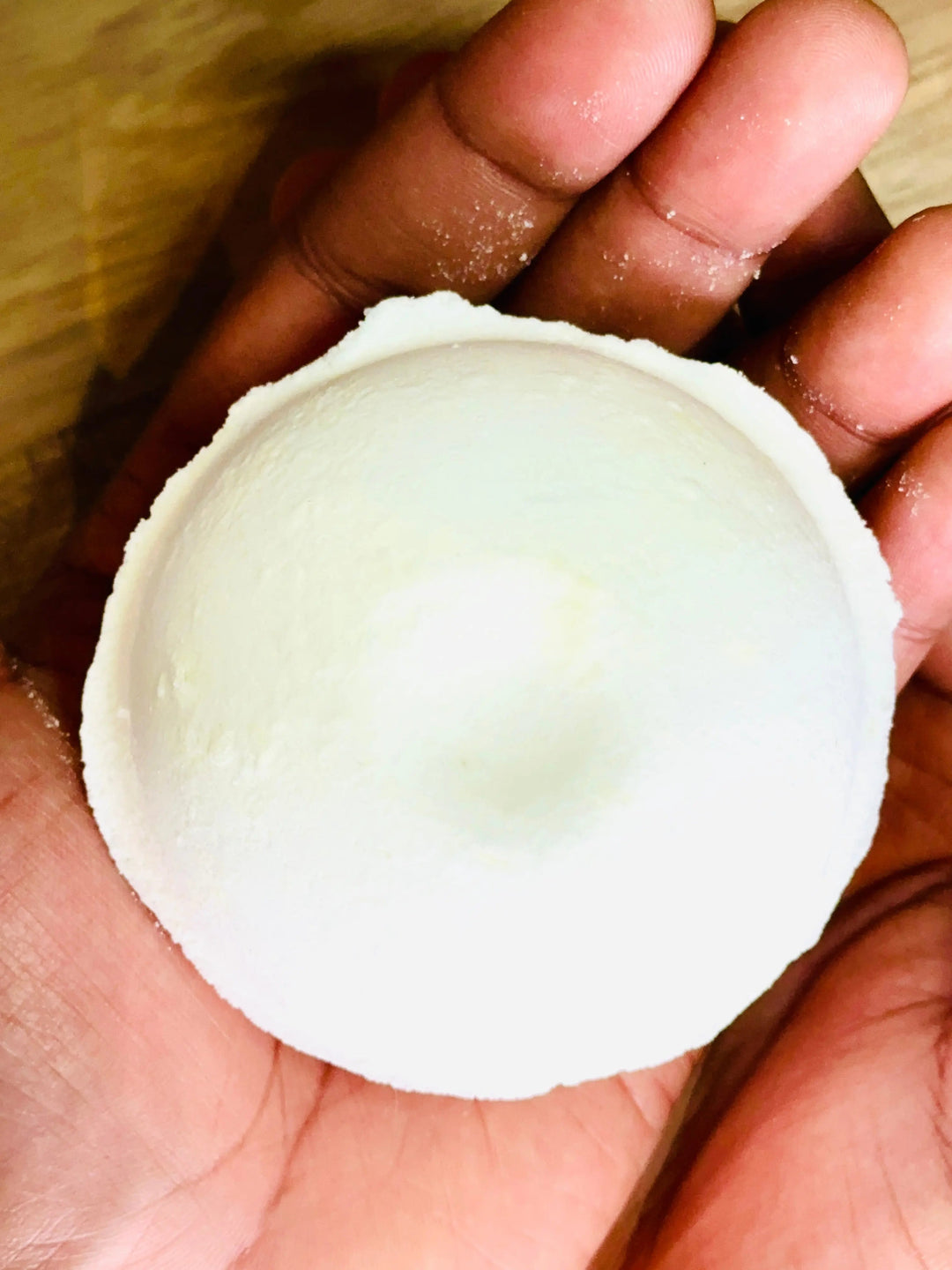 White round shower steamer held in a palm, smooth top