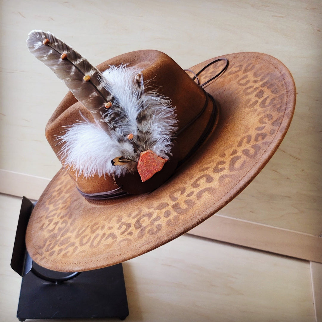 Feather and leather hat band with orange stone, shown on leopard-print hat