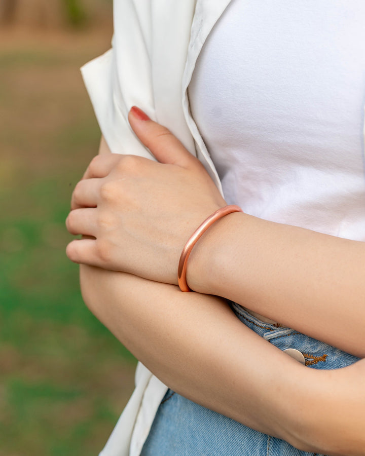 Rose-gold copper cuff bracelet worn on wrist