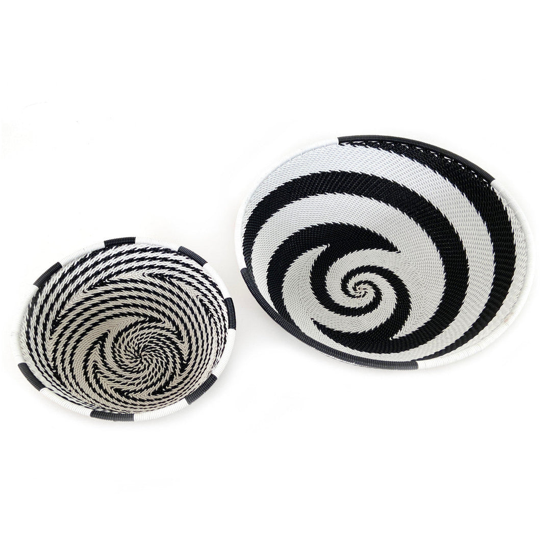 Two small woven wire basket bowls with black-and-white spiral motifs and white rims
