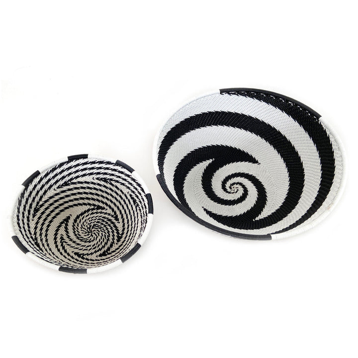 Two small woven wire basket bowls with black-and-white spiral motifs and white rims